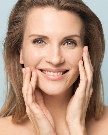 Model touching her face with a light blue background.