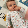 Pyjama modèle jungle porté par un bébé allongé sur un tapis, mettant en évidence la fermeture éclaire.