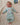 Bébé allongé sur tapis et souriant portant le pyjama "nager au lieu des coraux" de la collection mer.