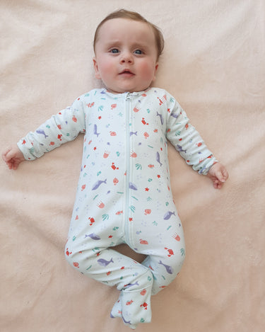 Bébé allongé vêtu de son pyjama de la collection mer.